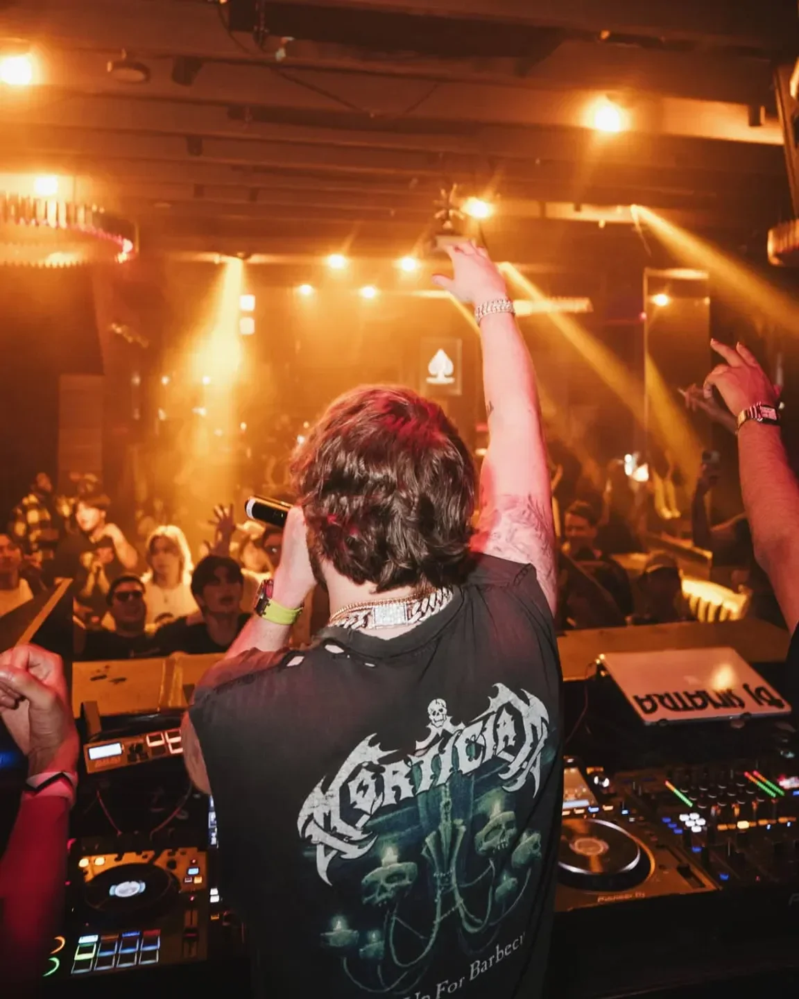 Energetic DJ performing at 1OAK nightclub in Tokyo with a crowd of people.