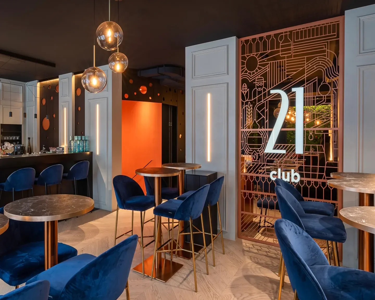 Stylish interior of 21 Club in Geneva, featuring velvet chairs and decorative lighting.