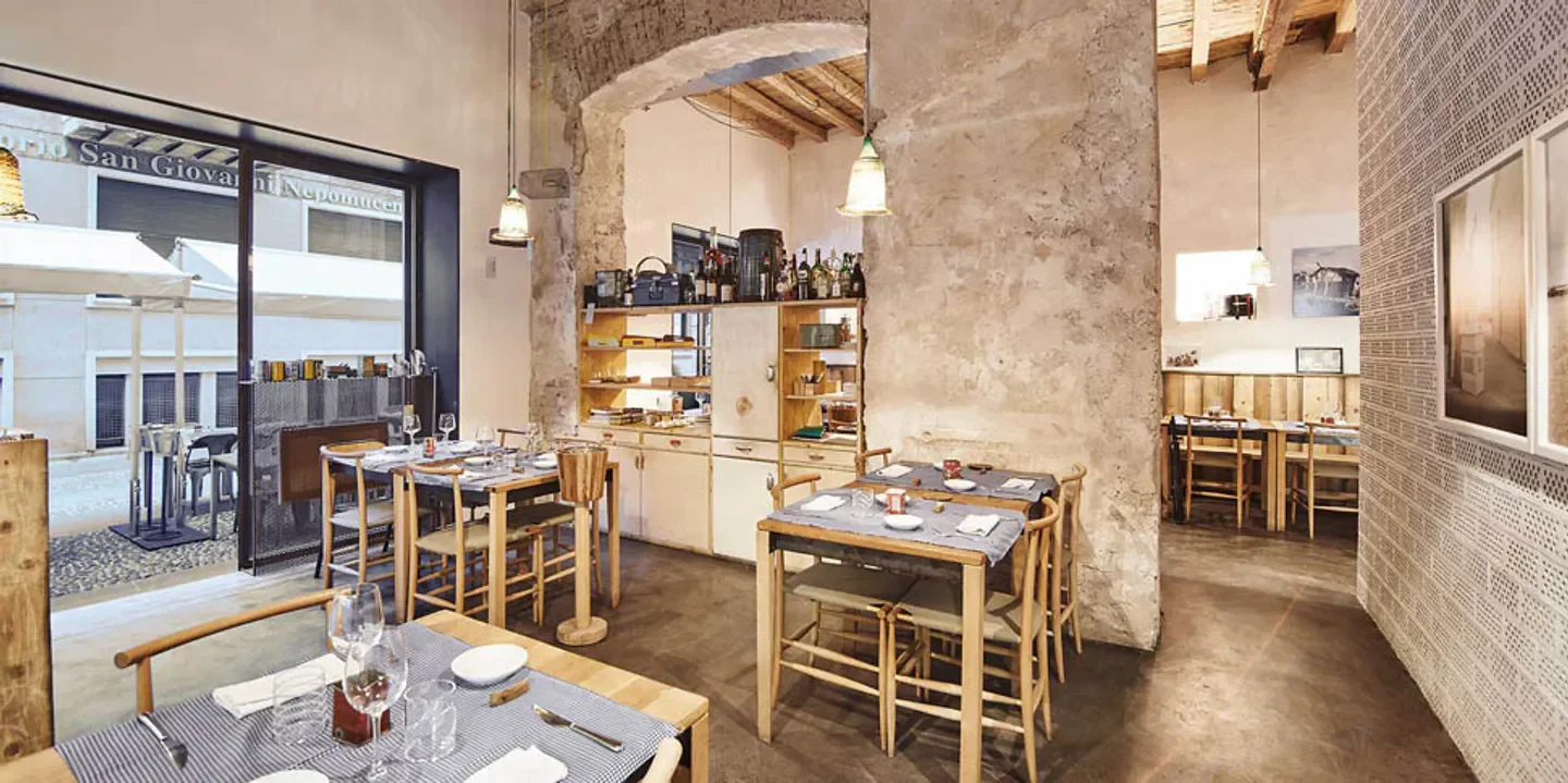 Interior of 28 Posti restaurant in Milan, featuring rustic design and dining tables.