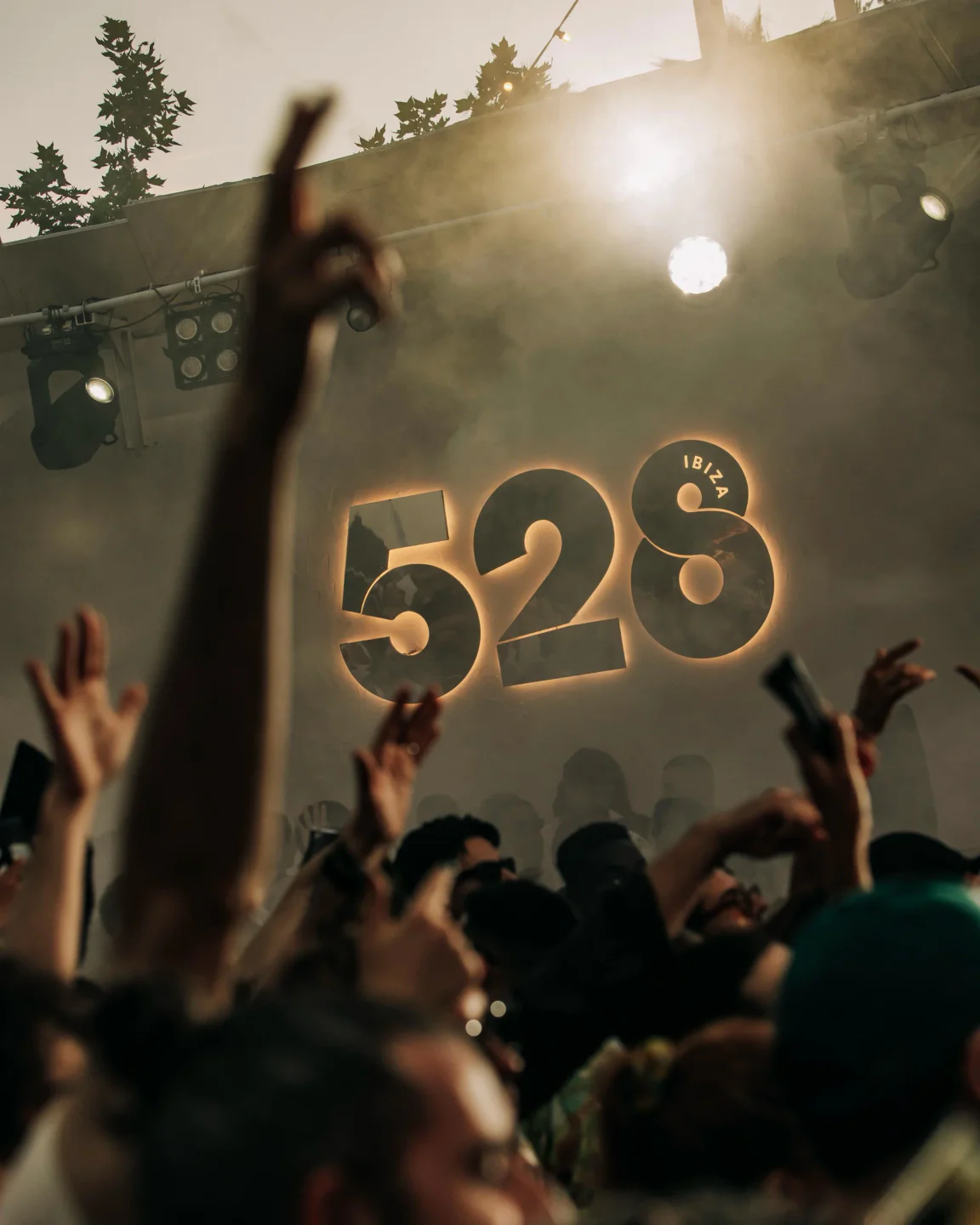 The glowing 528 Ibiza logo illuminates a foggy, energetic crowd at a nightclub with raised hands.