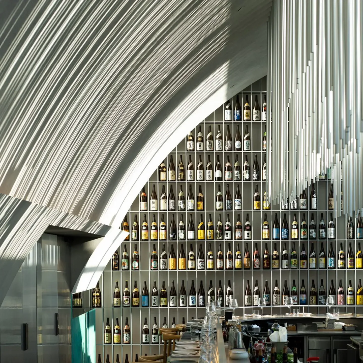 Interior of A by Yuval Ben Neriah restaurant in Tel Aviv, featuring sake bottles and modern design.