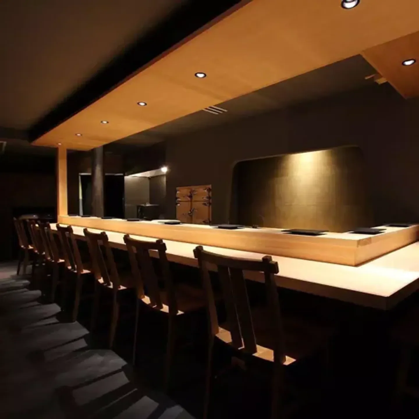 Interior of a canto in Osaka, showing the sushi bar and wooden chairs.