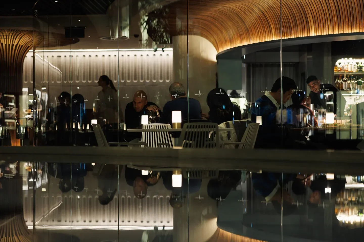 Stylish interior dining at AALIA restaurant in Sydney, with glass reflections.