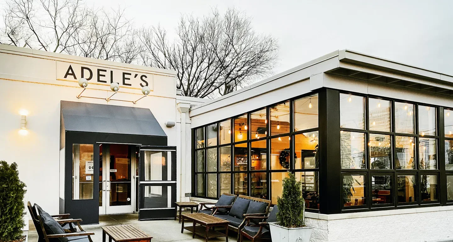 Exterior of Adele's Nashville restaurant in Nashville, with seating and large windows.