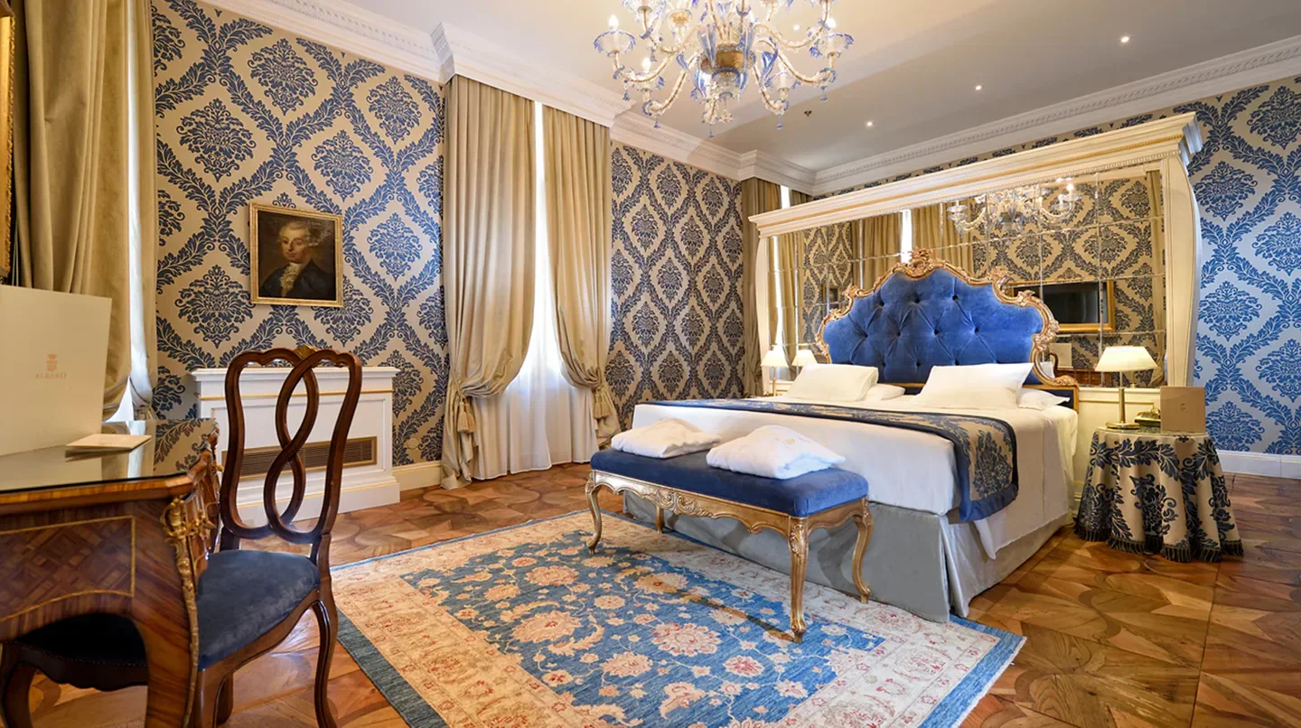 Elegant bedroom at Ai Reali di Venezia, Venice, with luxurious decor and a grand chandelier.