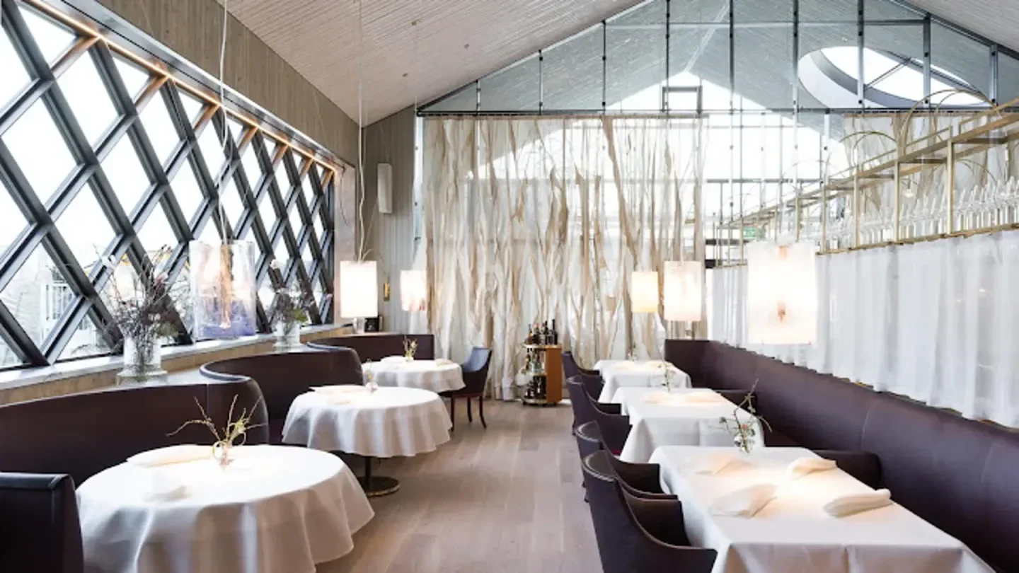 Elegant dining room interior at AIRA restaurant in Stockholm, featuring round tables and natural light.