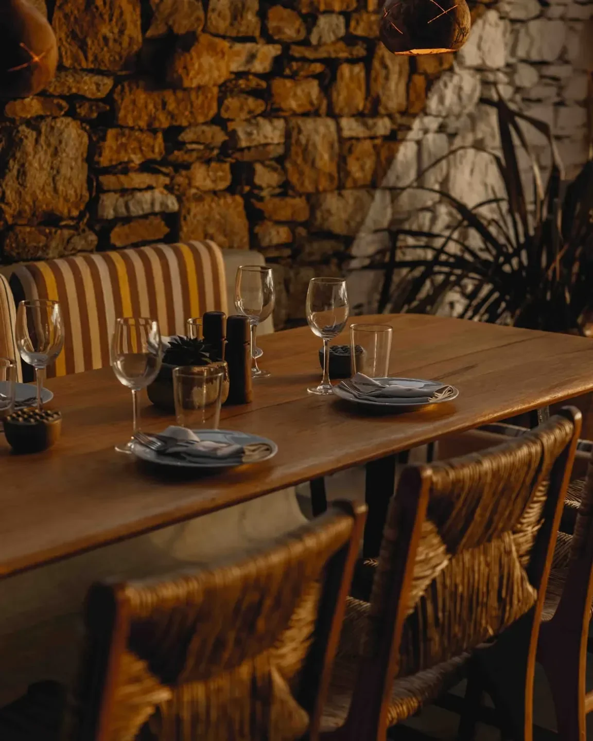 Cozy dining table at Alemagou restaurant in Mykonos, featuring stone wall backdrop.