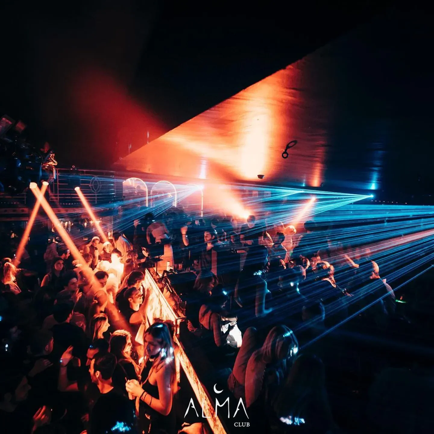 Energetic crowd and laser show inside Alma Club nightclub in Paris, creating a vibrant atmosphere.