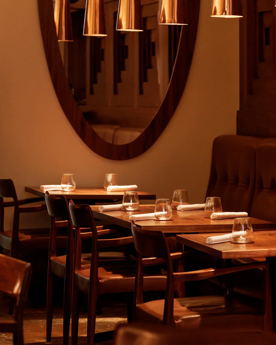 Cozy interior of Alma restaurant in Lisbon, Portugal, featuring wooden tables, chairs, and elegant lighting.