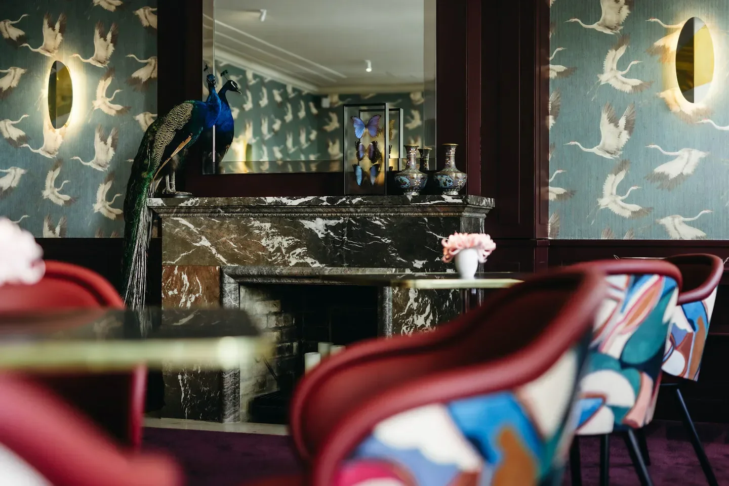 Elegant interior at Alois - Dallmayr Fine Dining in Munich, featuring peacock and fireplace