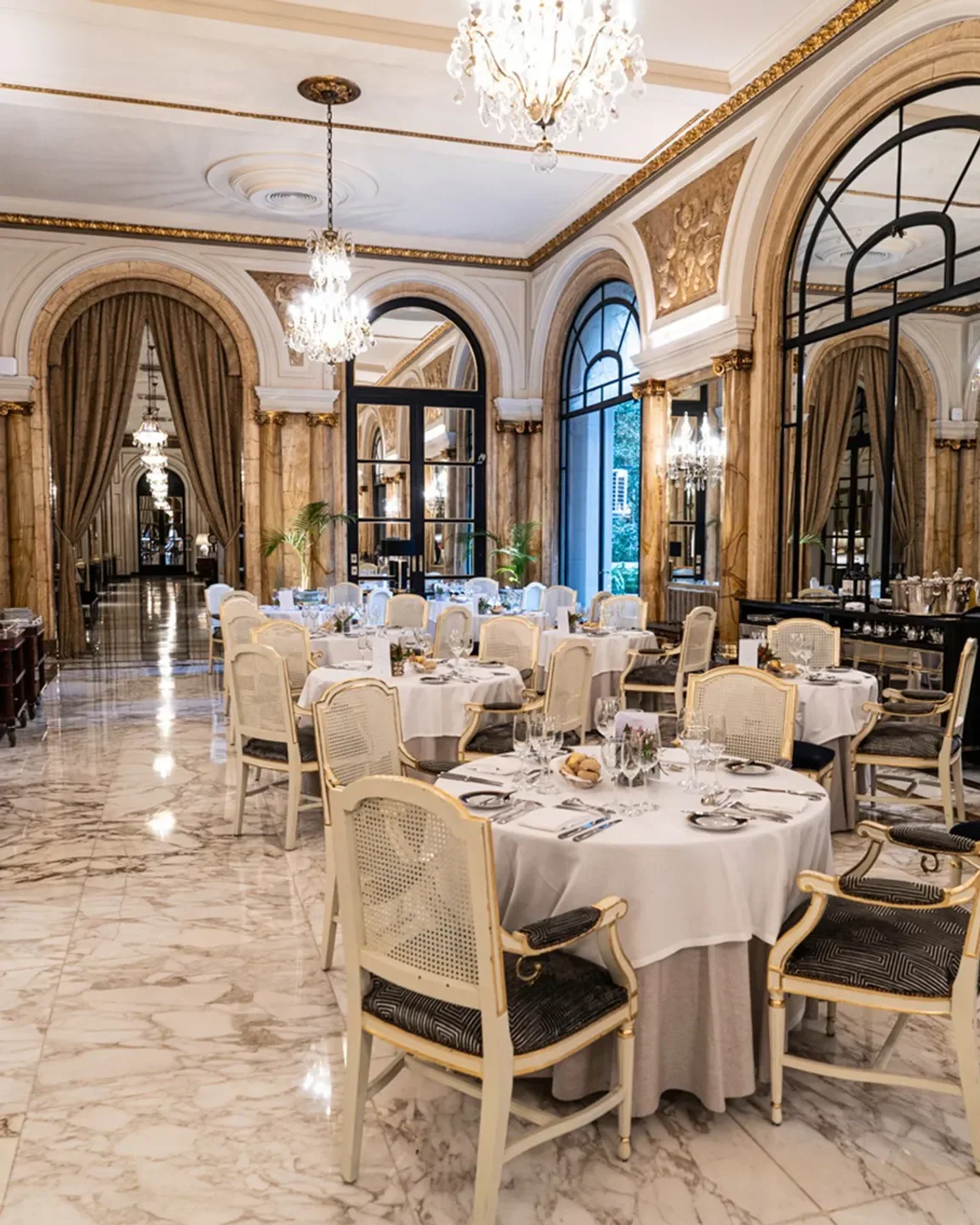 Elegant dining room at Alvear Lobby Bar in Buenos Aires, featuring chandeliers and marble floors.