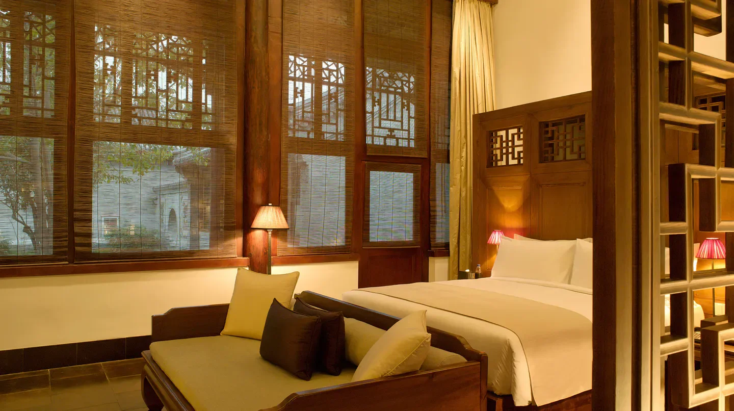 Cozy bedroom at Aman Summer Palace in Beijing with wooden details and garden view