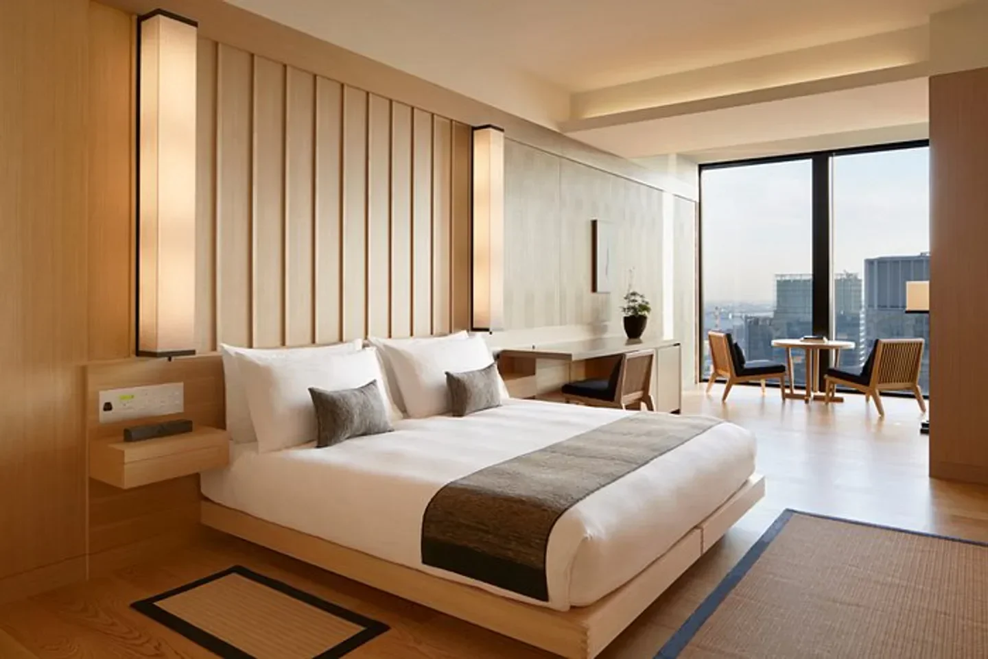 Minimalist bedroom at Aman Tokyo hotel, offering panoramic city views of Tokyo.