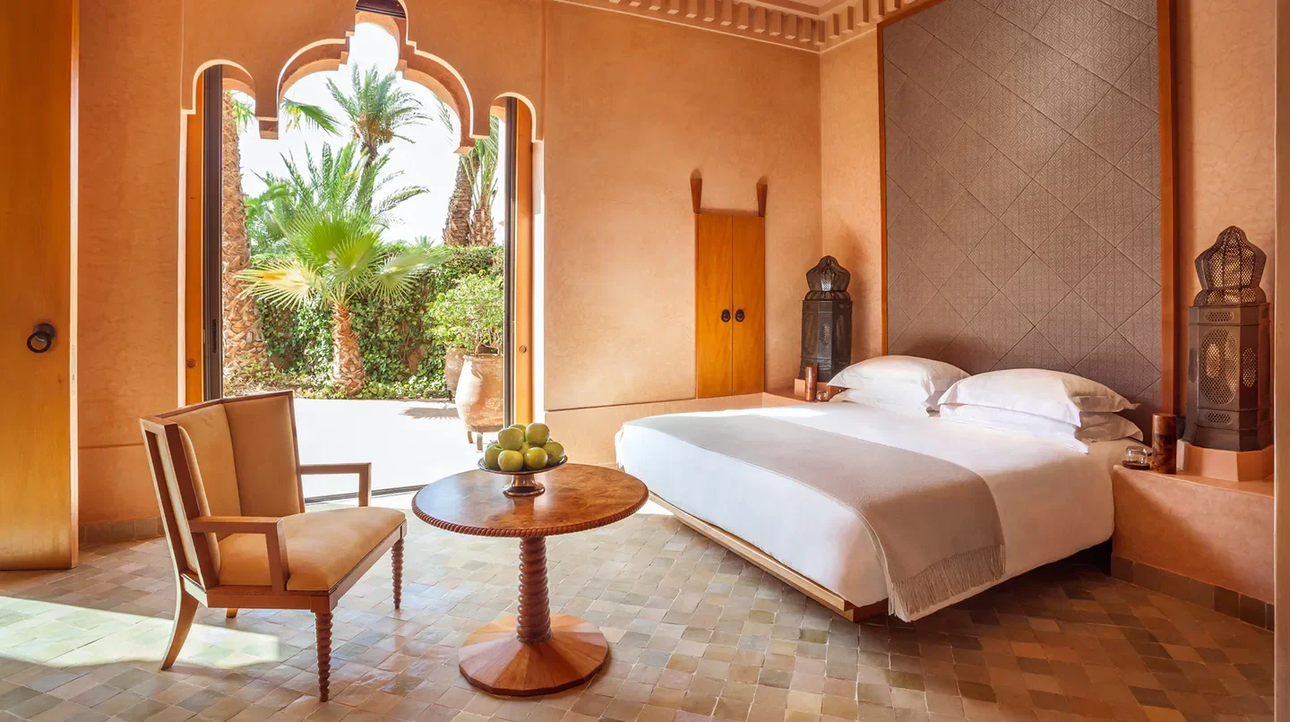 Elegant bedroom at Amanjena in Marrakech, with garden view and luxurious decor.