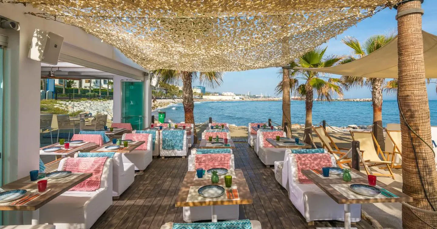 Outdoor dining at Amare Beach restaurant in Marbella, with sea views and palm trees.