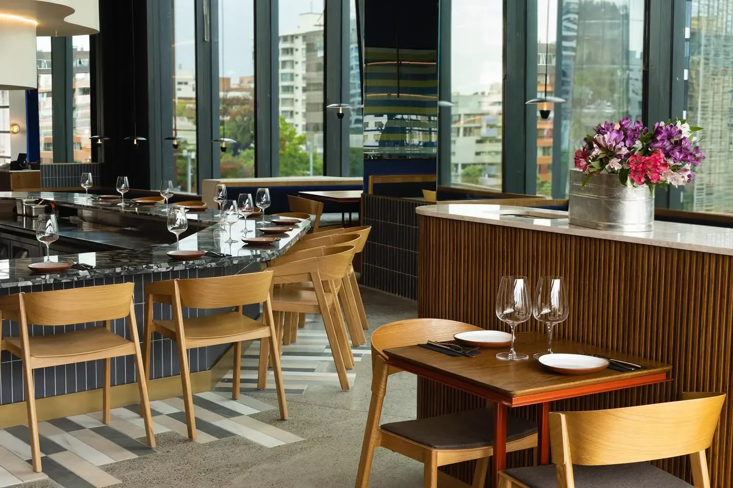 Interior of Ambrosía Bistro in Santiago: stylish dining area with city views and flowers.