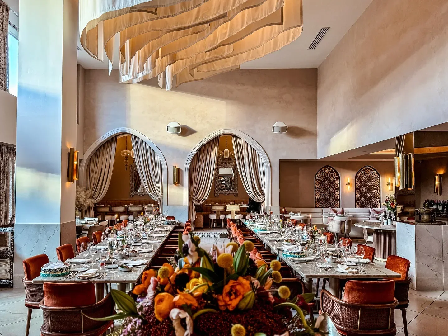 Elegant dining room at Ammoora restaurant in Baltimore, with flowers and long tables.