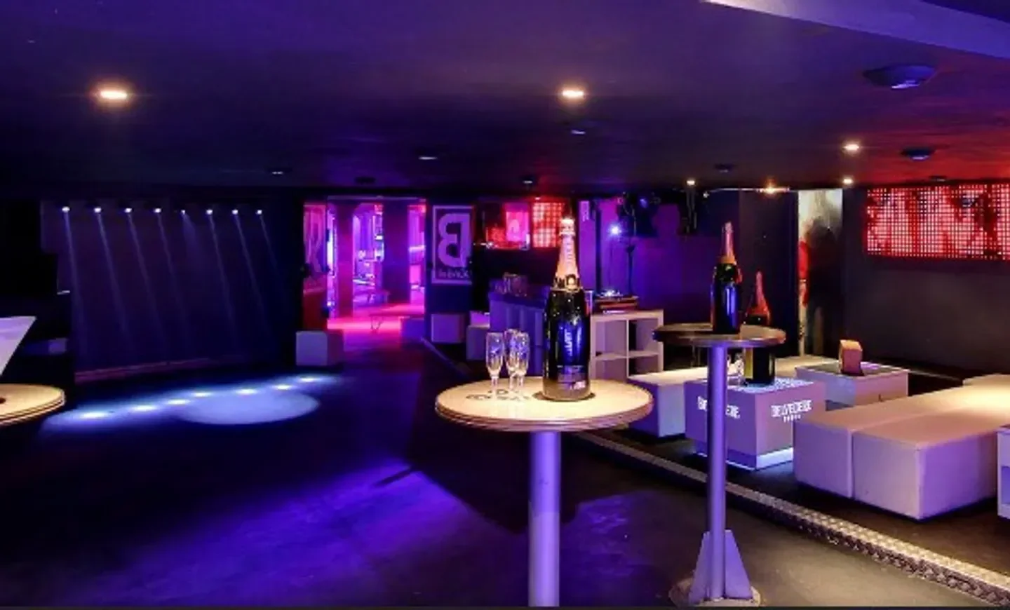 Interior view of Amnesia Club in Chamonix, with tables, champagne, and colorful lighting.