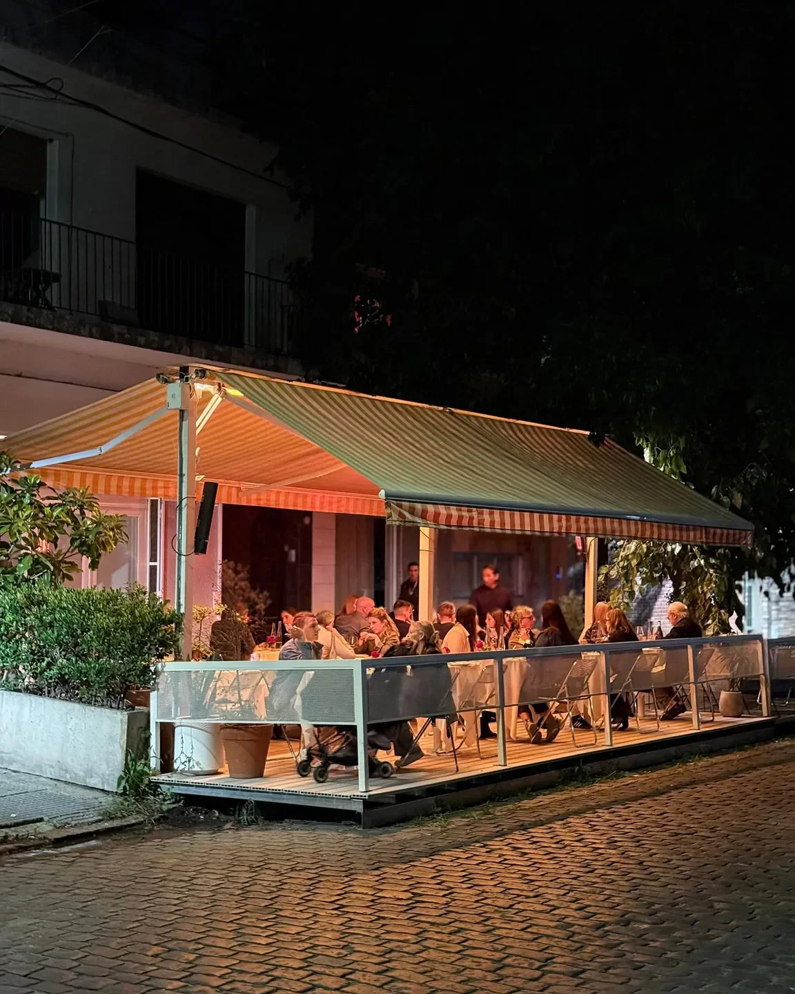 Outdoor dining at Anafe restaurant in Buenos Aires, illuminated at night with guests.