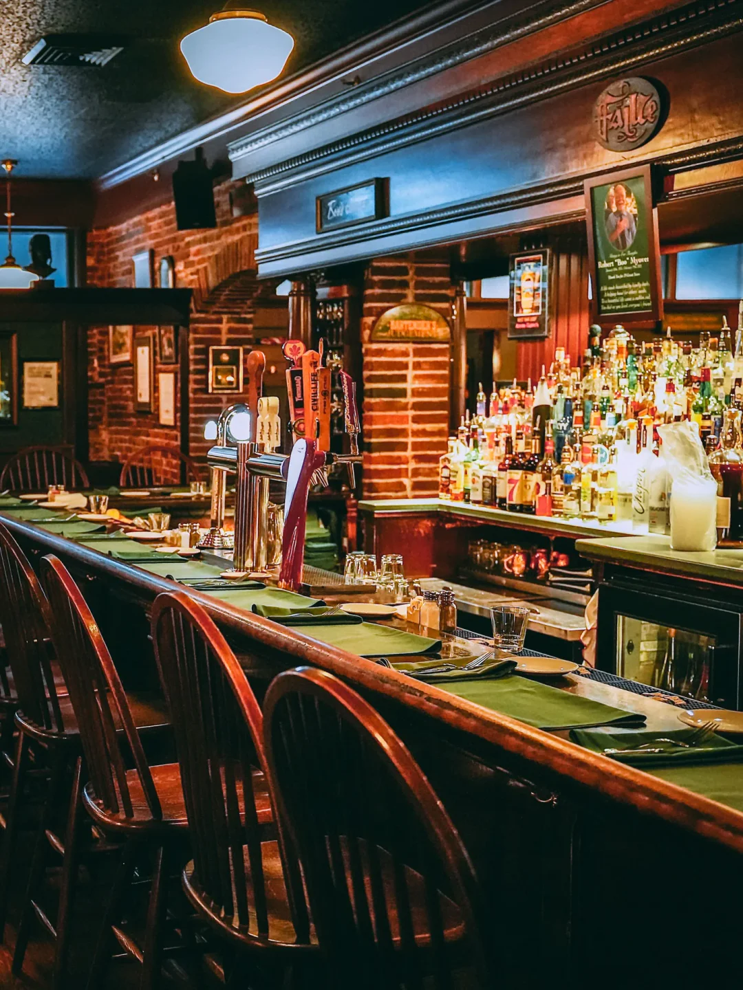 Cozy bar interior at Annie Gunn's in St. Louis, featuring wooden chairs, well-stocked bar, and ambient lighting.
