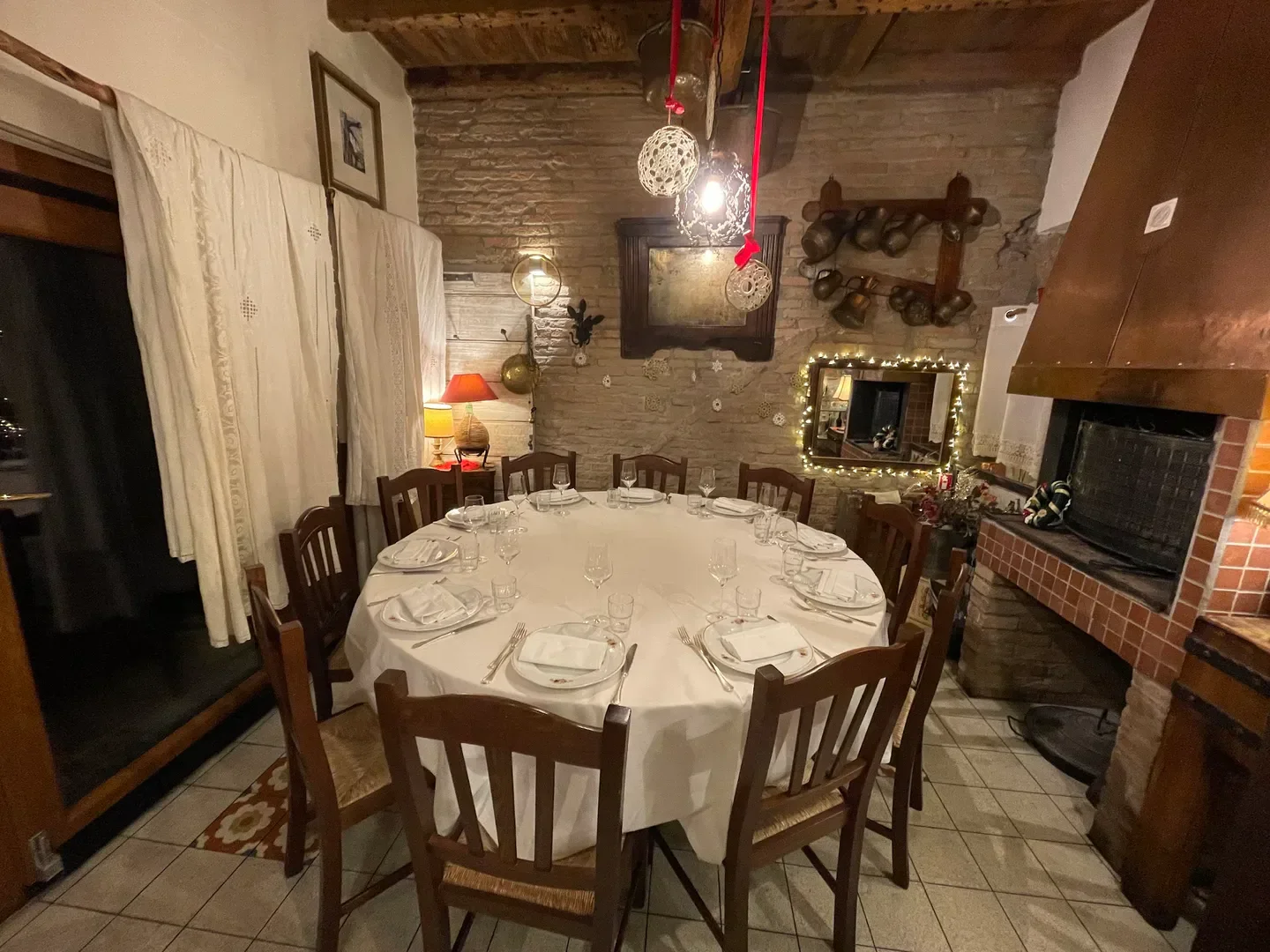 Cozy dining room at Antica Osteria del Mirasole in Emilia-Romagna, Italy, with fireplace and tables.