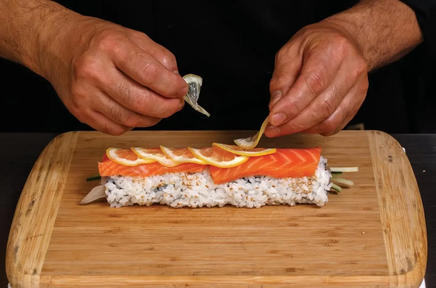 Chef preparing sushi roll at ANZU restaurant in San Francisco, adding lemon zest.