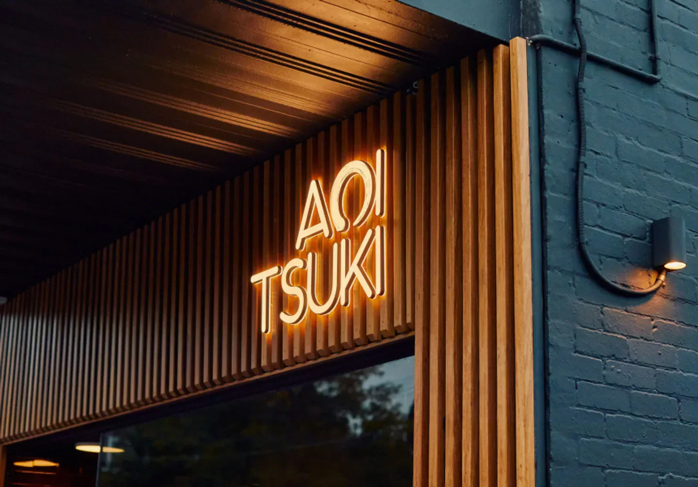 Glowing AOI TSUKI sign in Melbourne, showcasing the restaurant's entrance and facade design.