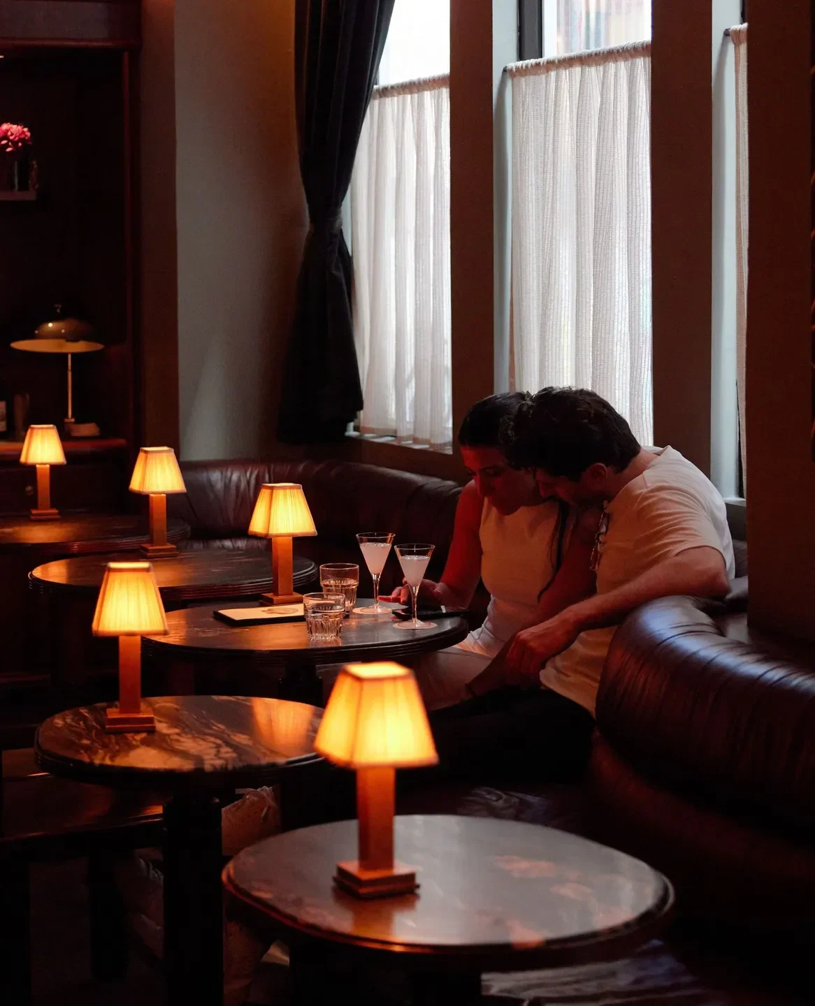 Cozy couple at Apollo Inn restaurant in Melbourne, surrounded by warm table lamps and cocktails.