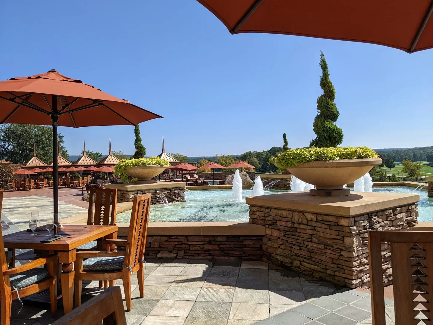 Outdoor dining at Aqueous at Nemacolin in Virginia Beach with fountains and umbrellas.