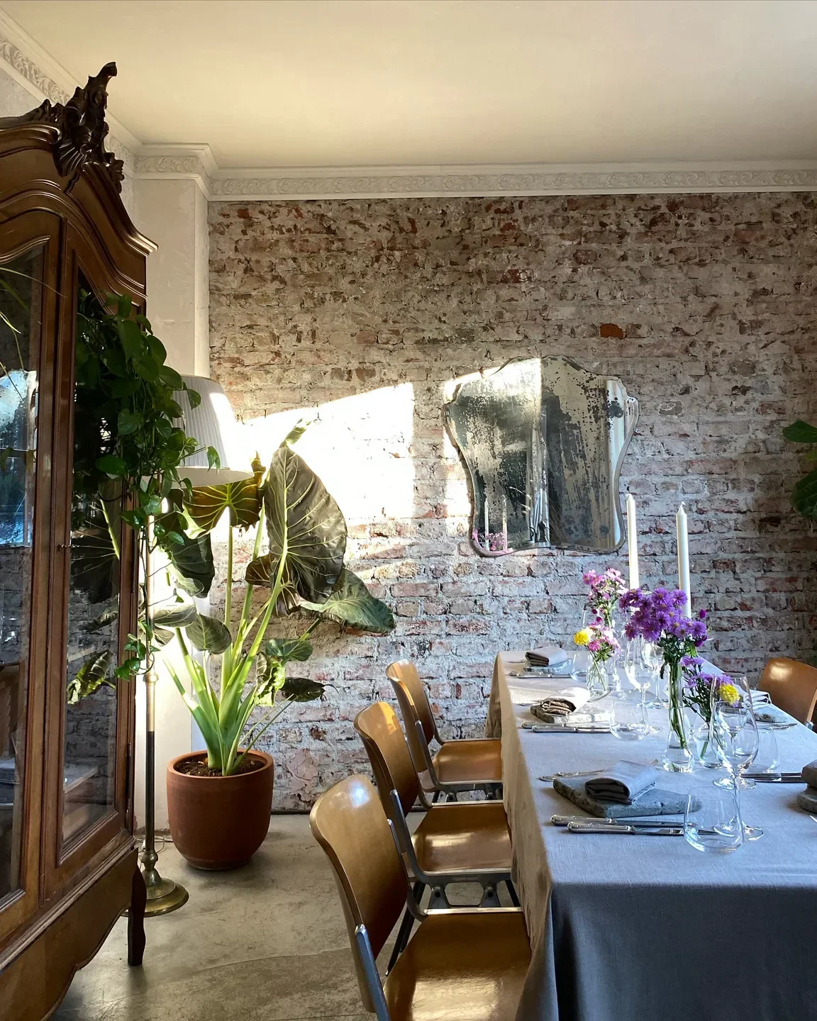 Araka Istanbul: Elegant dining room with brick wall, set table, and antique cabinet