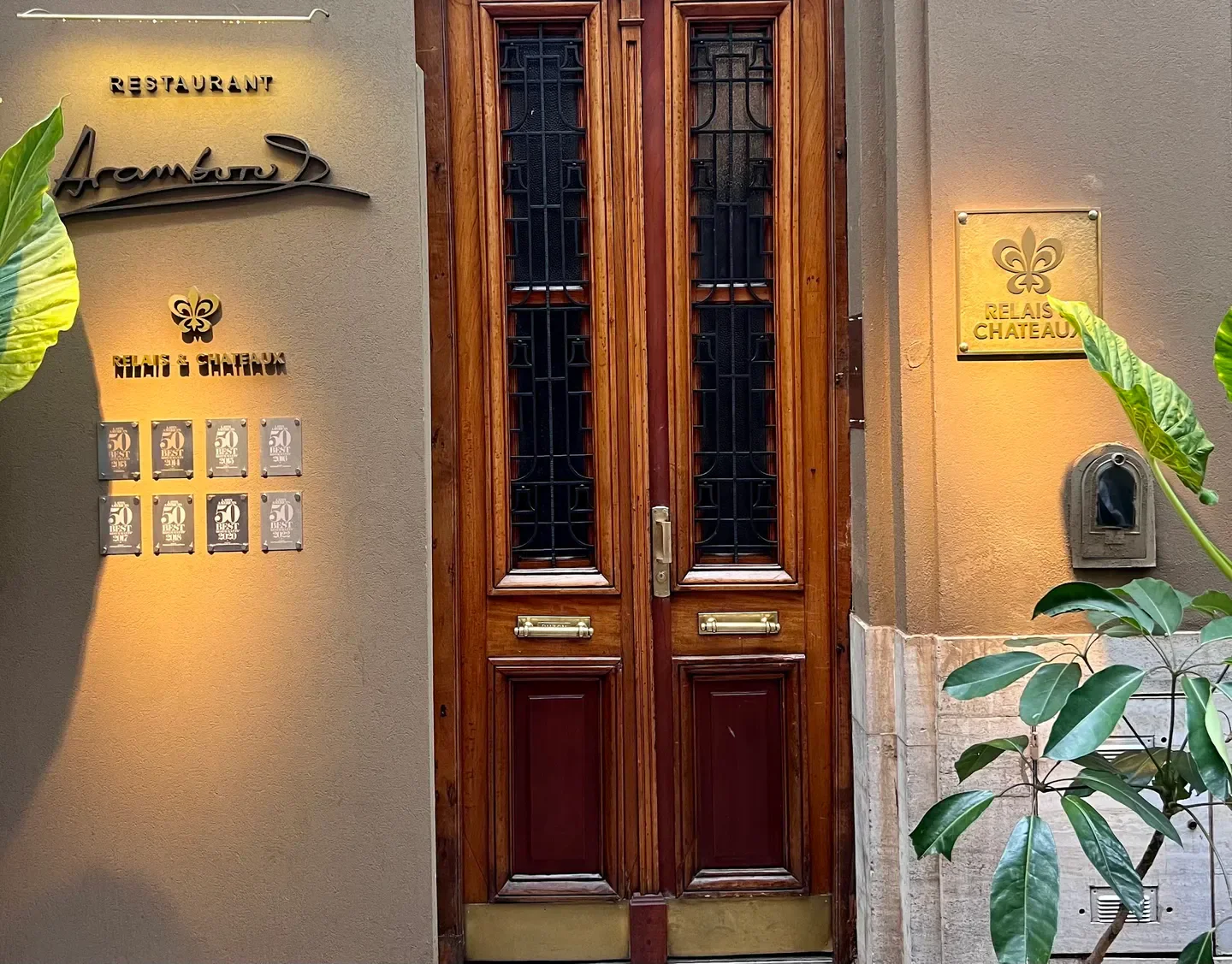 Entrance of Aramburu restaurant in Buenos Aires, featuring wooden door and awards.