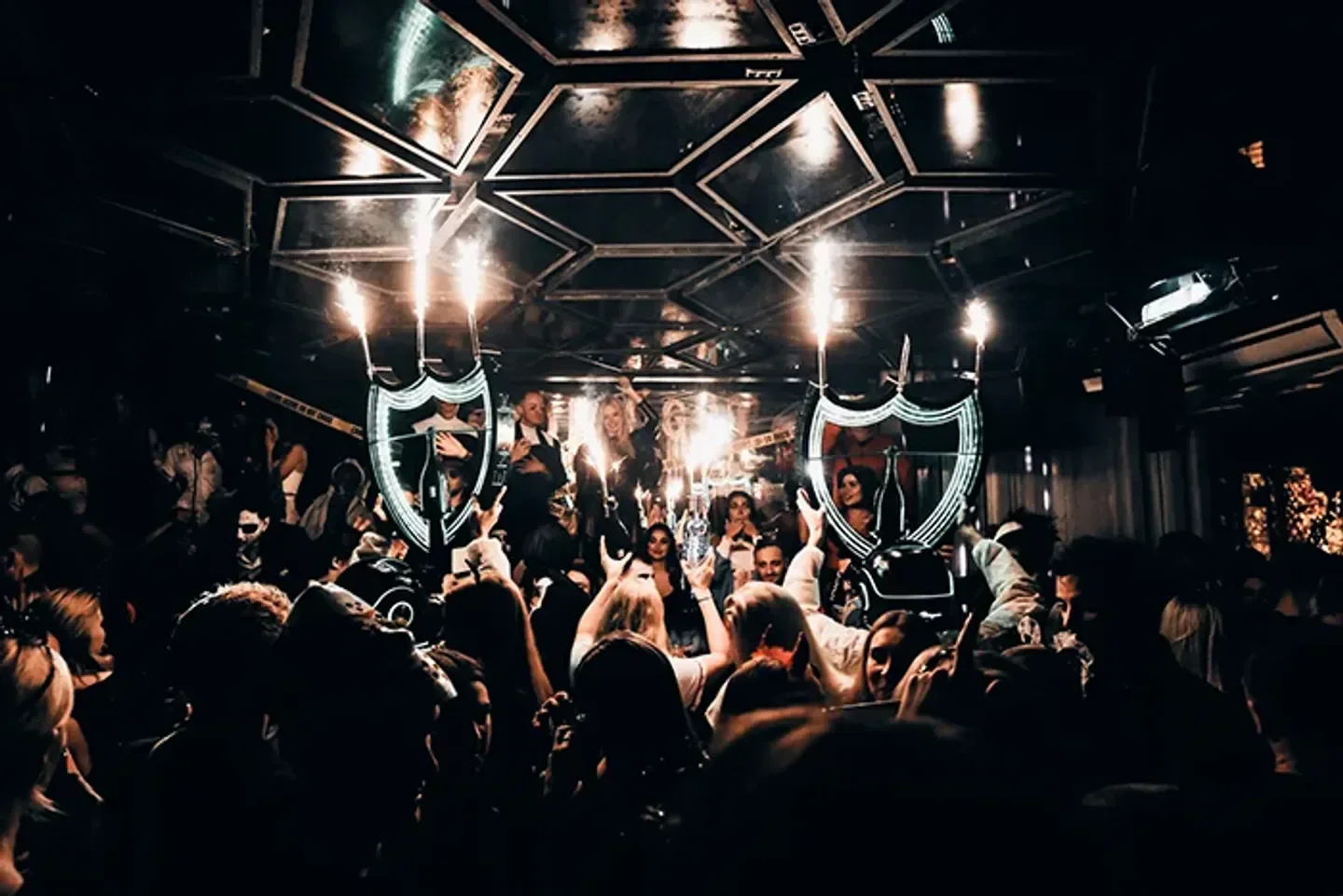Energetic party scene at ARCH nightclub in Copenhagen, with champagne bottles and sparkling lights.