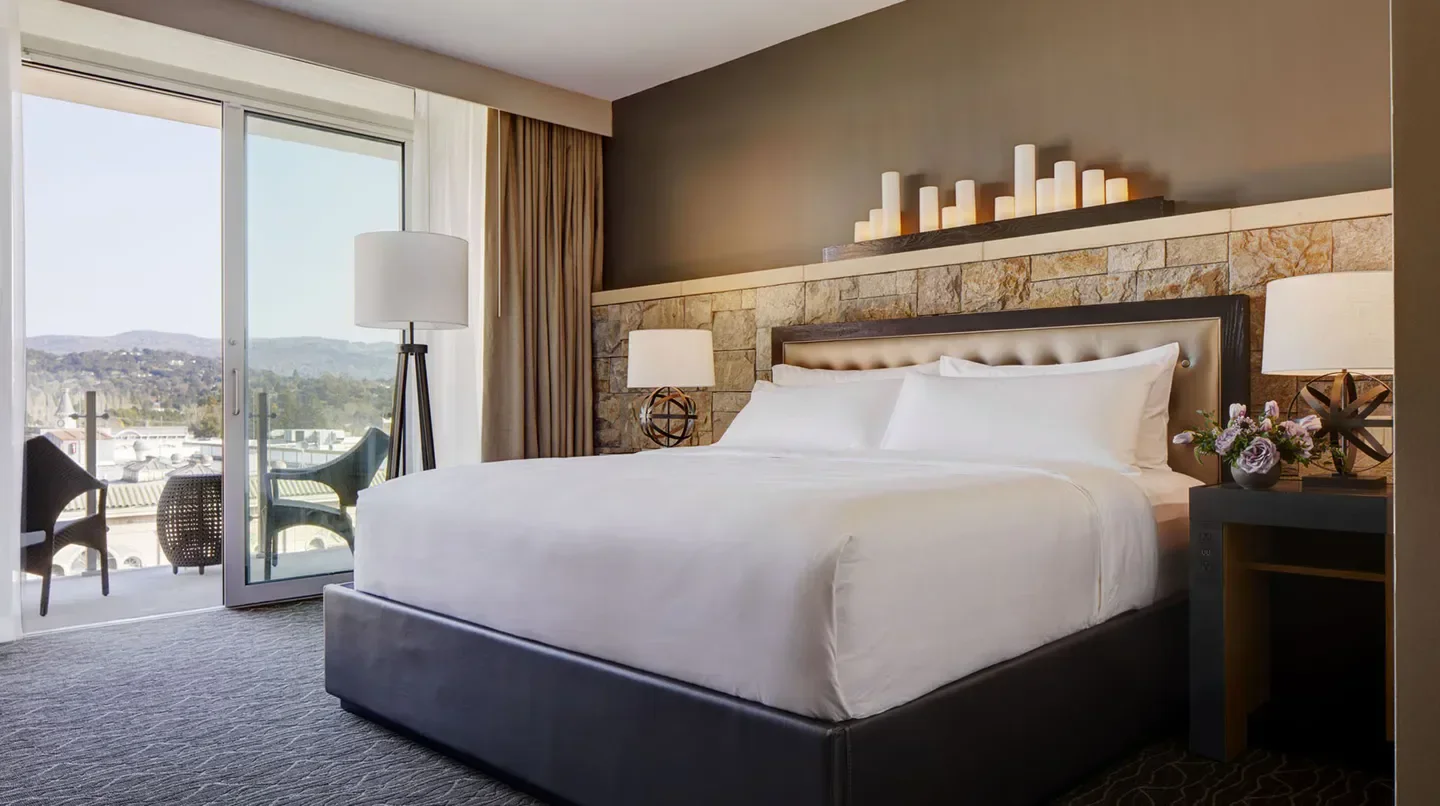 Spacious bedroom at Archer Hotel Napa with a balcony overlooking Napa Valley.