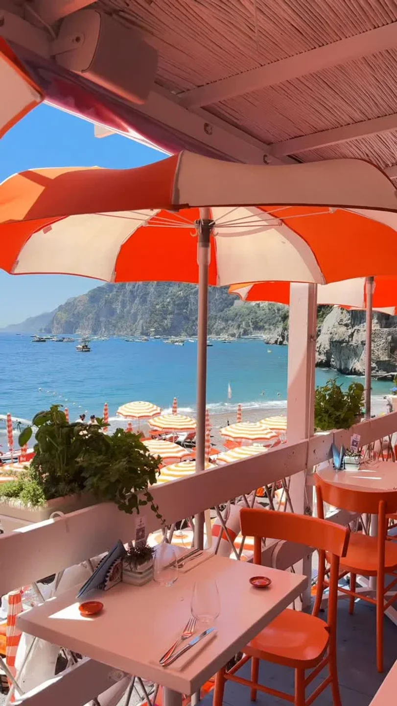 Arienzo Beach Club restaurant seating with view of the vibrant Amalfi Coast waters and beach umbrellas