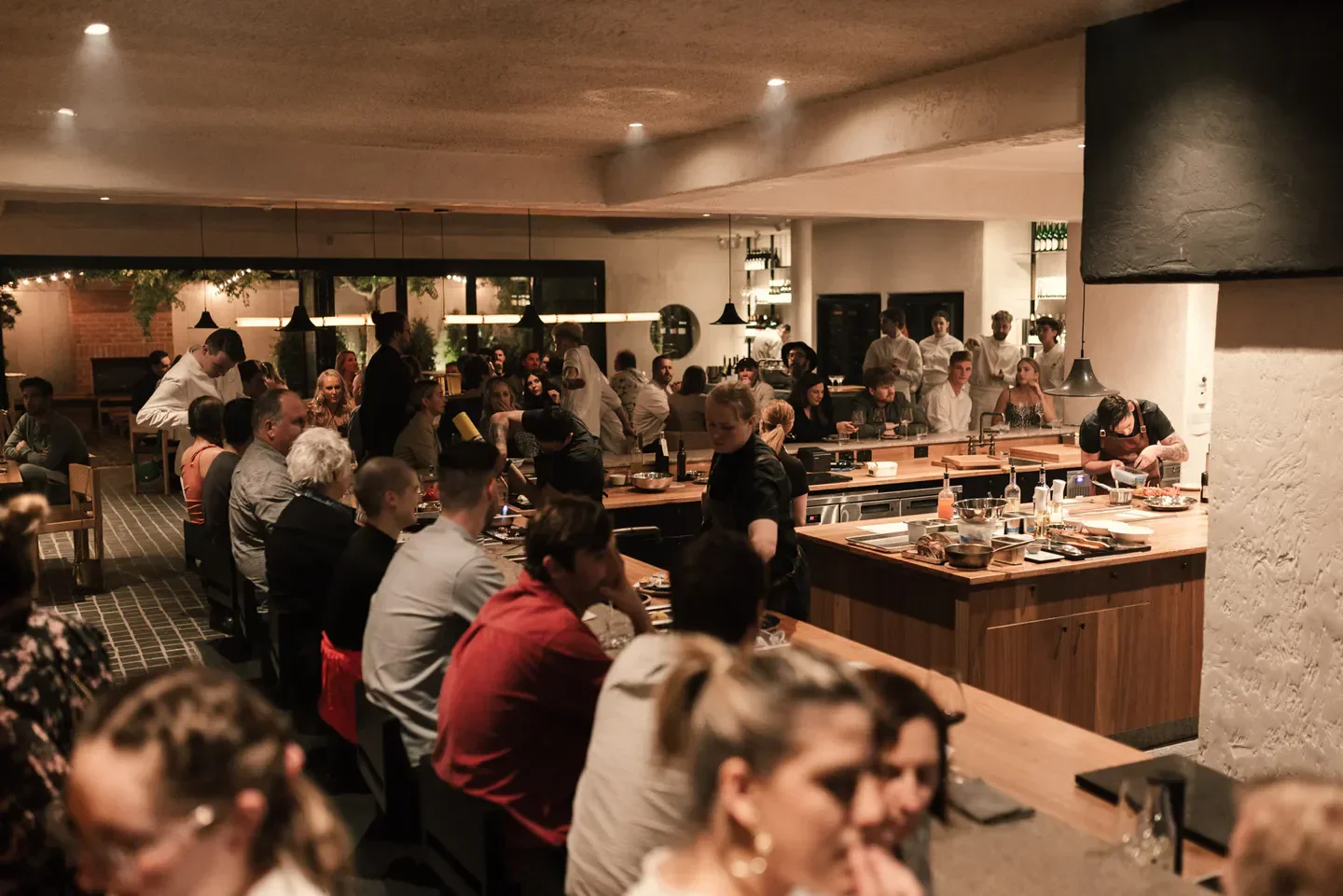 Busy interior of Arkhé restaurant in Adelaide, with chefs preparing food for diners.