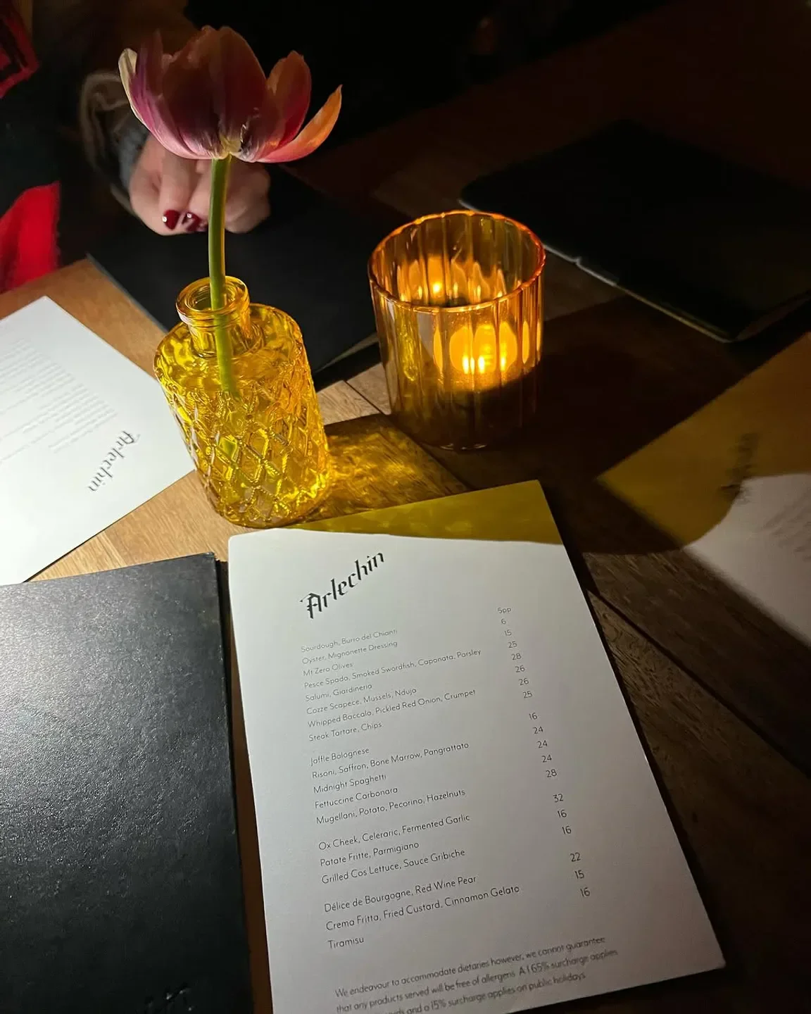 Table setting at Arlechin restaurant in Melbourne, featuring flower, candle, and menu.