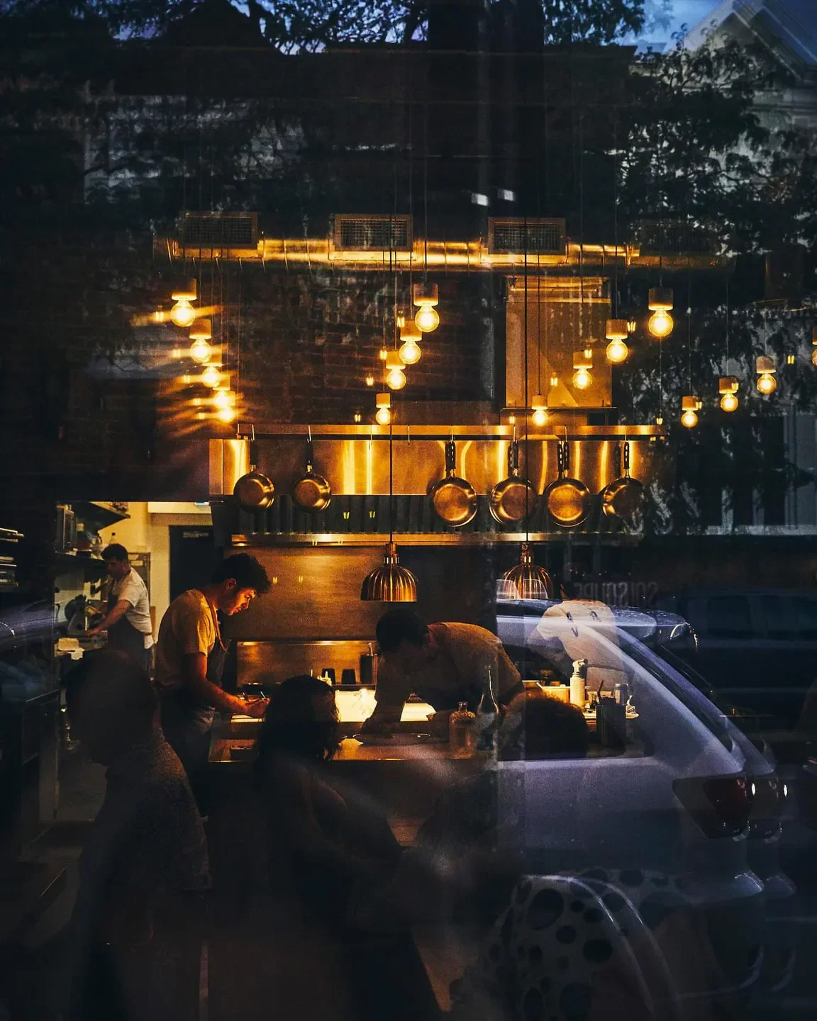 Interior view of Arvi restaurant in Quebec City, with cooks and hanging lights.