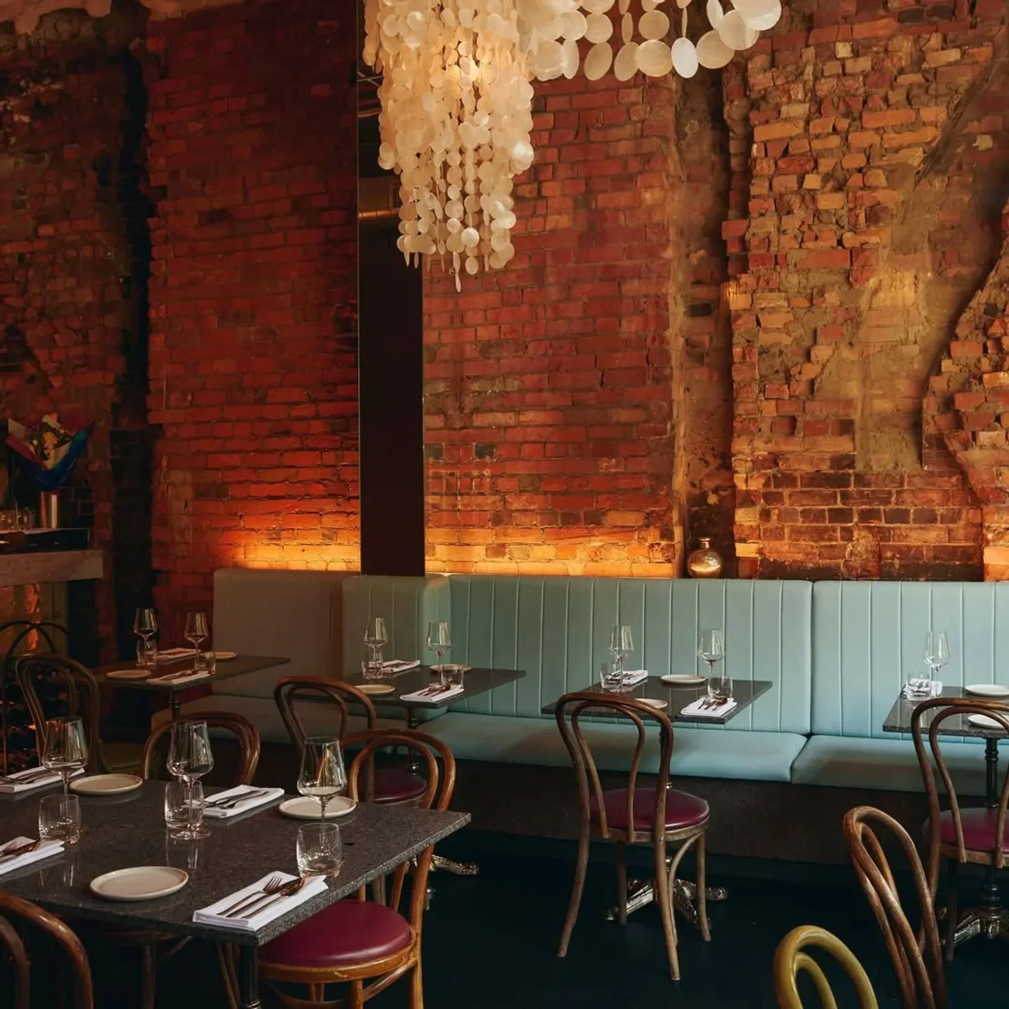 Cozy dining area at Askal restaurant in Melbourne, with exposed brick and elegant tables.