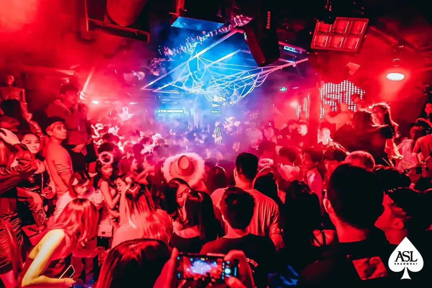 Energetic nightclub scene at ASL Shanghai, packed with people and vibrant red lighting.
