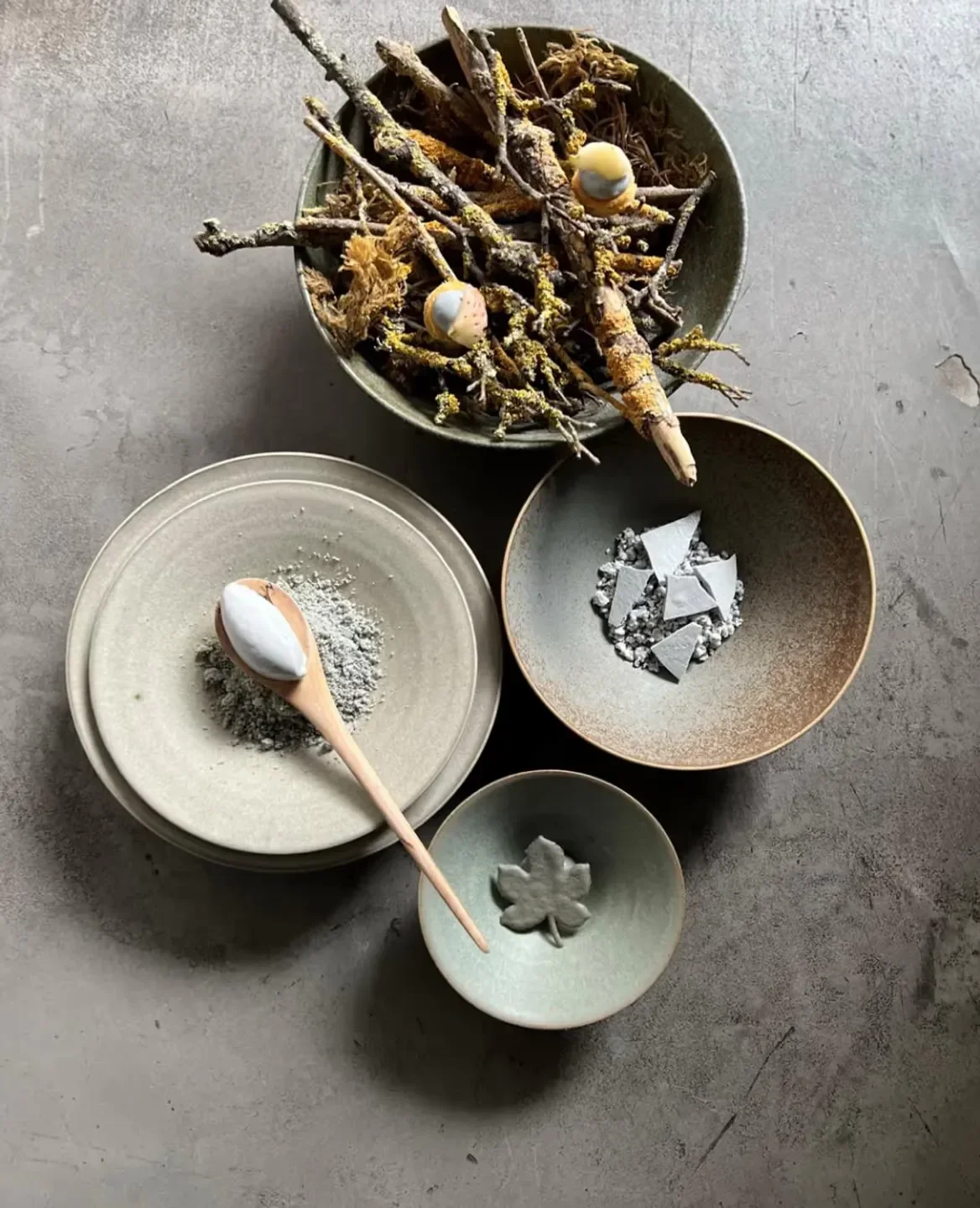 Artistic plating details at A.T restaurant in Paris: bowls, wood, and a leaf.