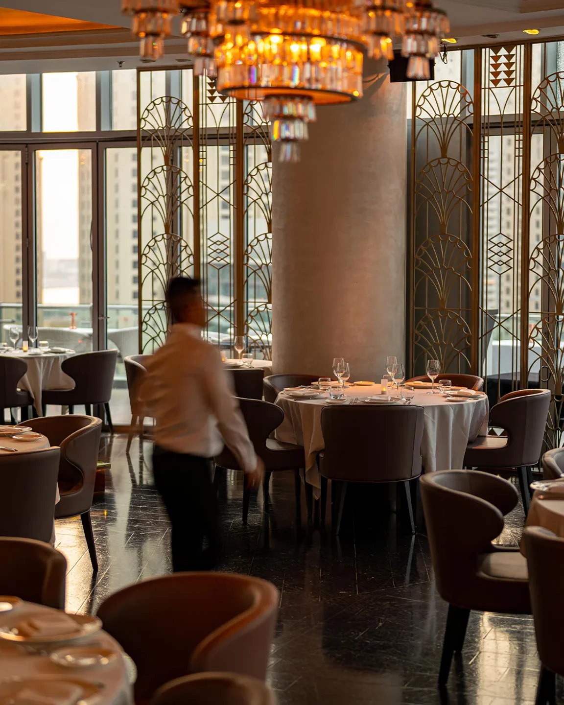 Atelier M Dubai: elegant interior with art deco screens, chandeliers, and table settings.