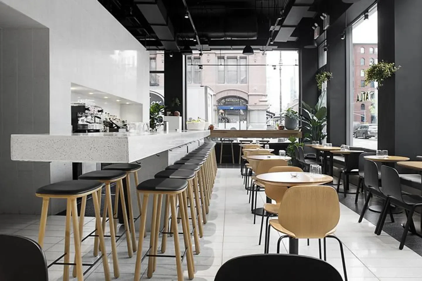 Minimalist interior of ATLA Noho in New York City with bar stools and tables.