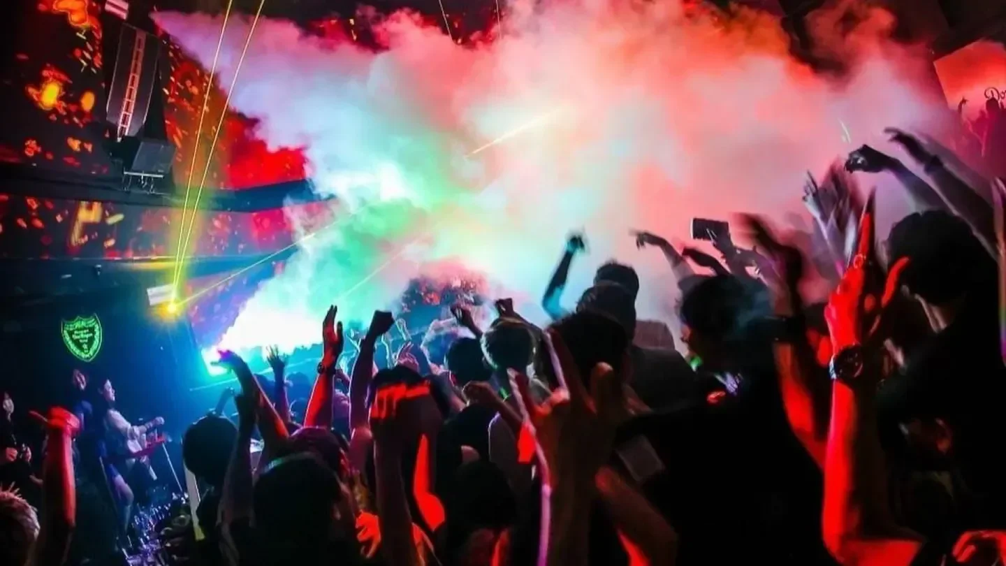 Energetic crowd at ATOM nightclub in Tokyo with colorful lights and atmosphere.