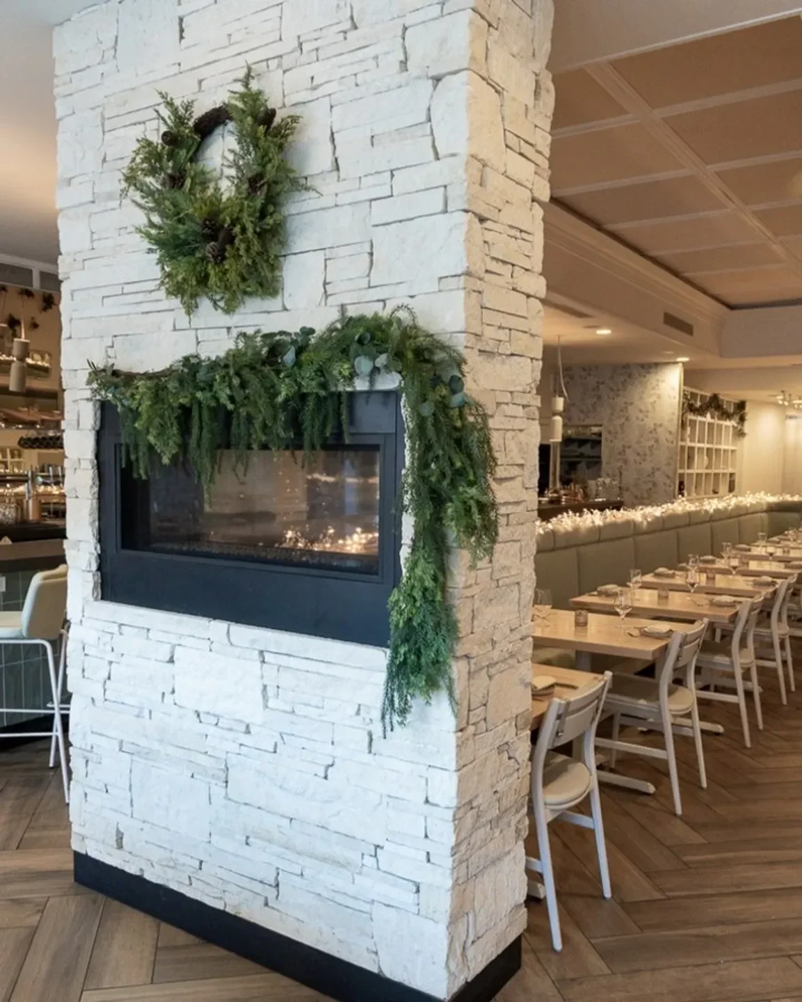 Cozy fireplace at Atria restaurant in Flagstaff, with holiday decor and dining tables.