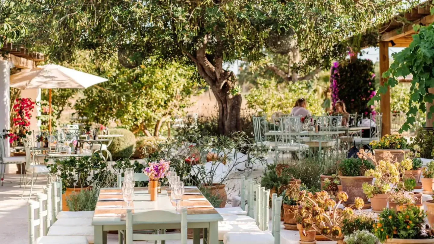 Outdoor dining at Aubergine restaurant in Ibiza, surrounded by lush greenery and flowers.