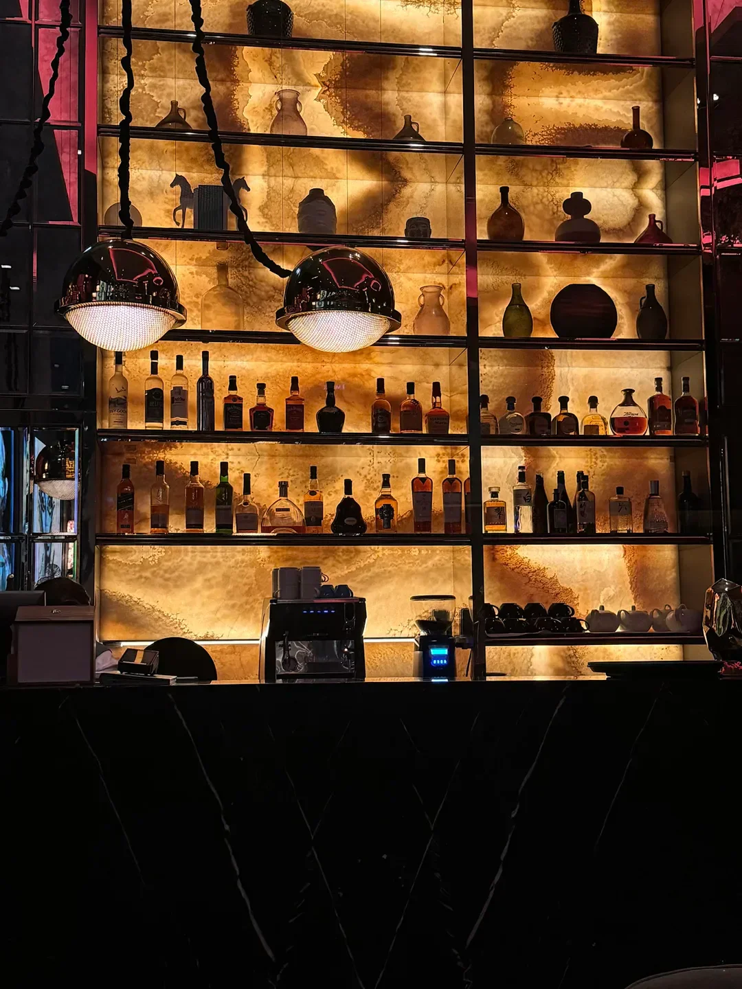 Elegant bar interior at August restaurant in Dubai, featuring backlit shelves and stylish decor.