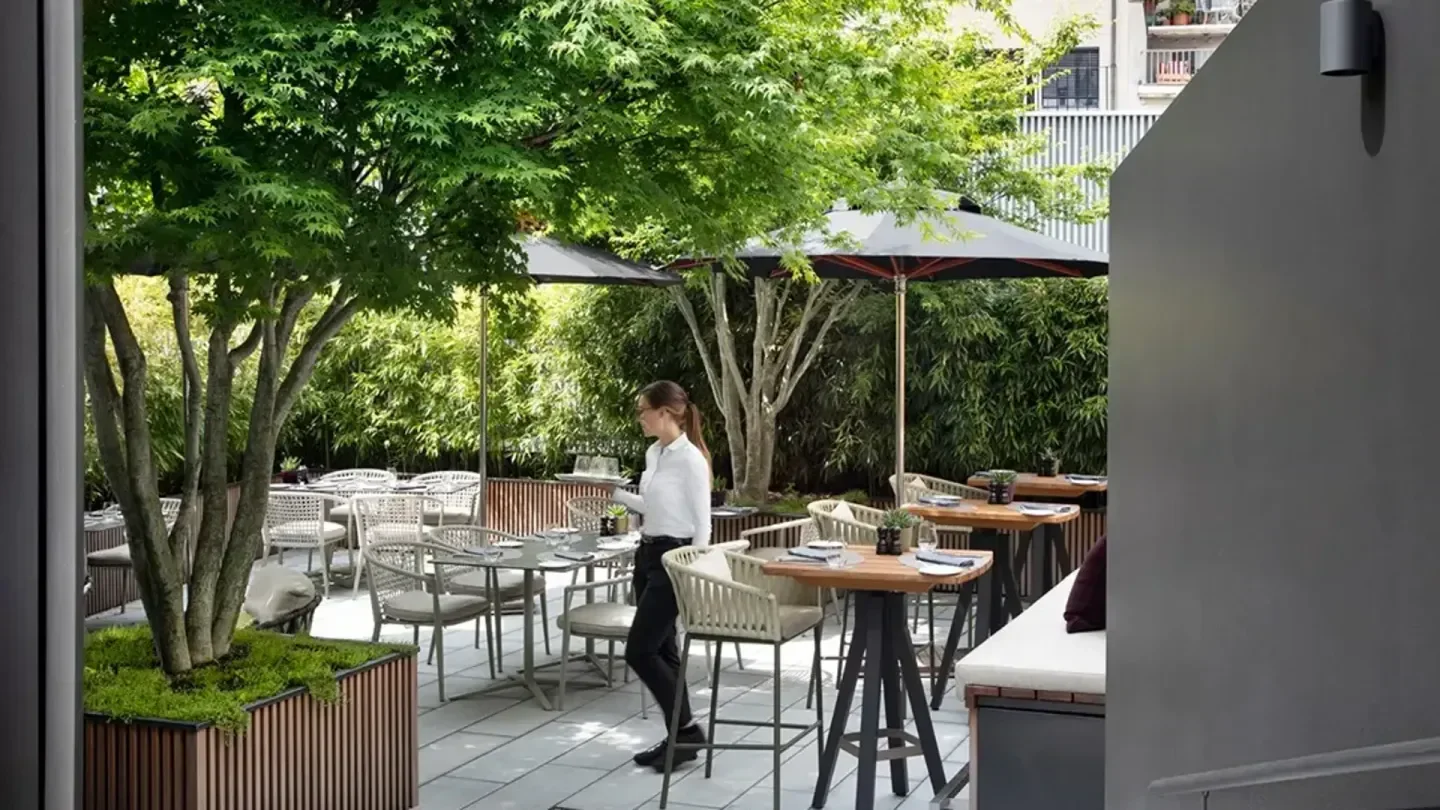 Outdoor dining at August restaurant in Zurich, Switzerland, with a waitress serving.