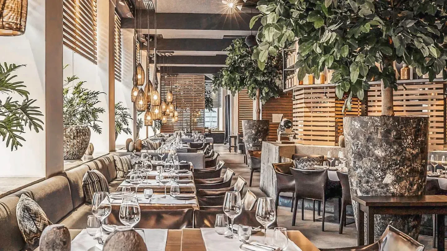 Interior of Aura nightclub in Zurich, featuring elegant lighting and lush greenery.