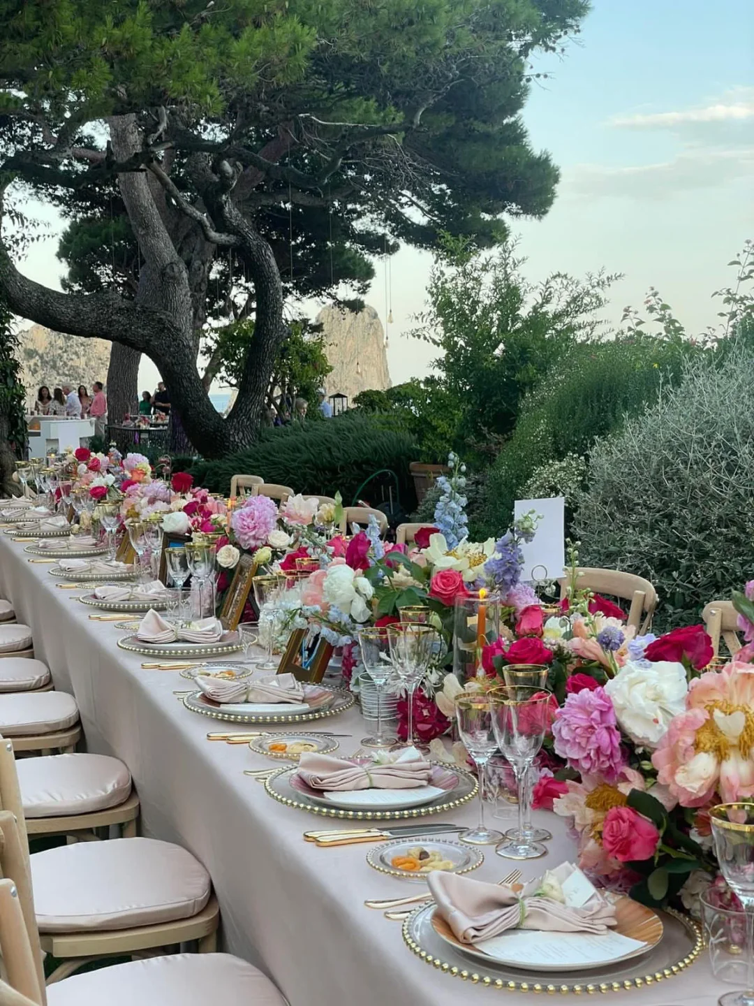Exquisite floral centerpieces adorn a long banquet table at Aurora restaurant in Capri, set for an outdoor dining experience.