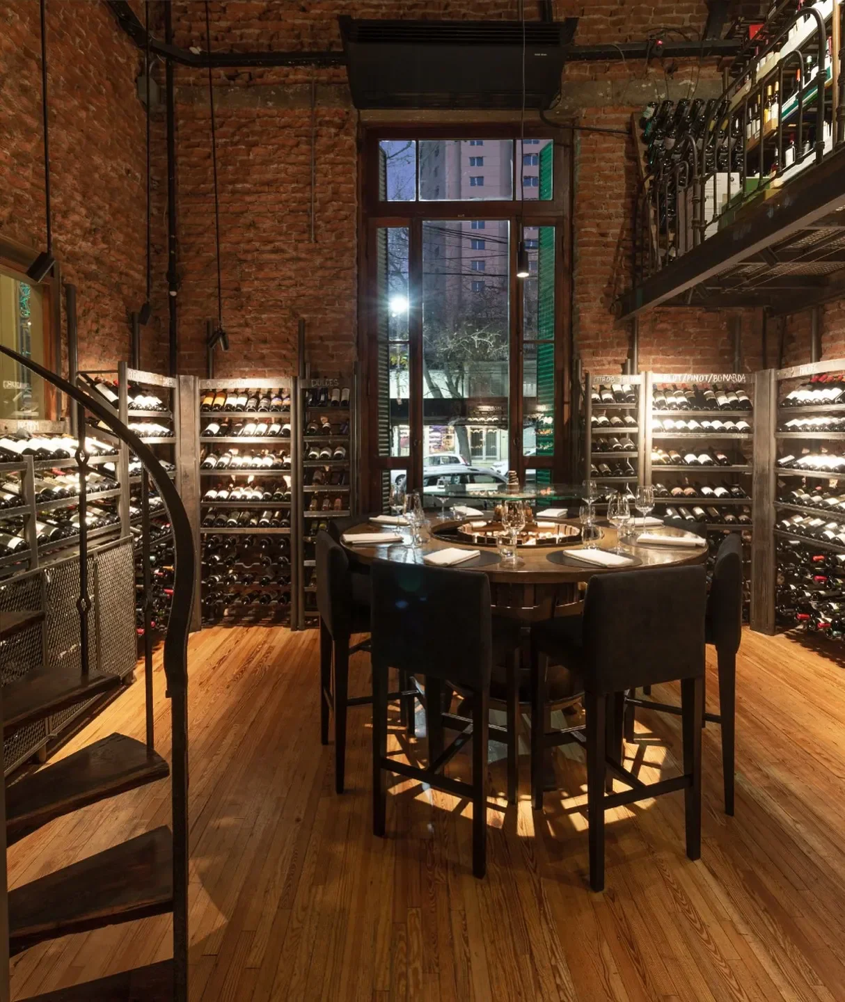 Cozy dining area at Azafrán restaurant in Mendoza with wine racks and a spiral staircase